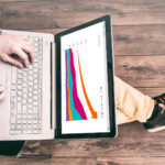 Man working at computer laptop with the finance report on the sc